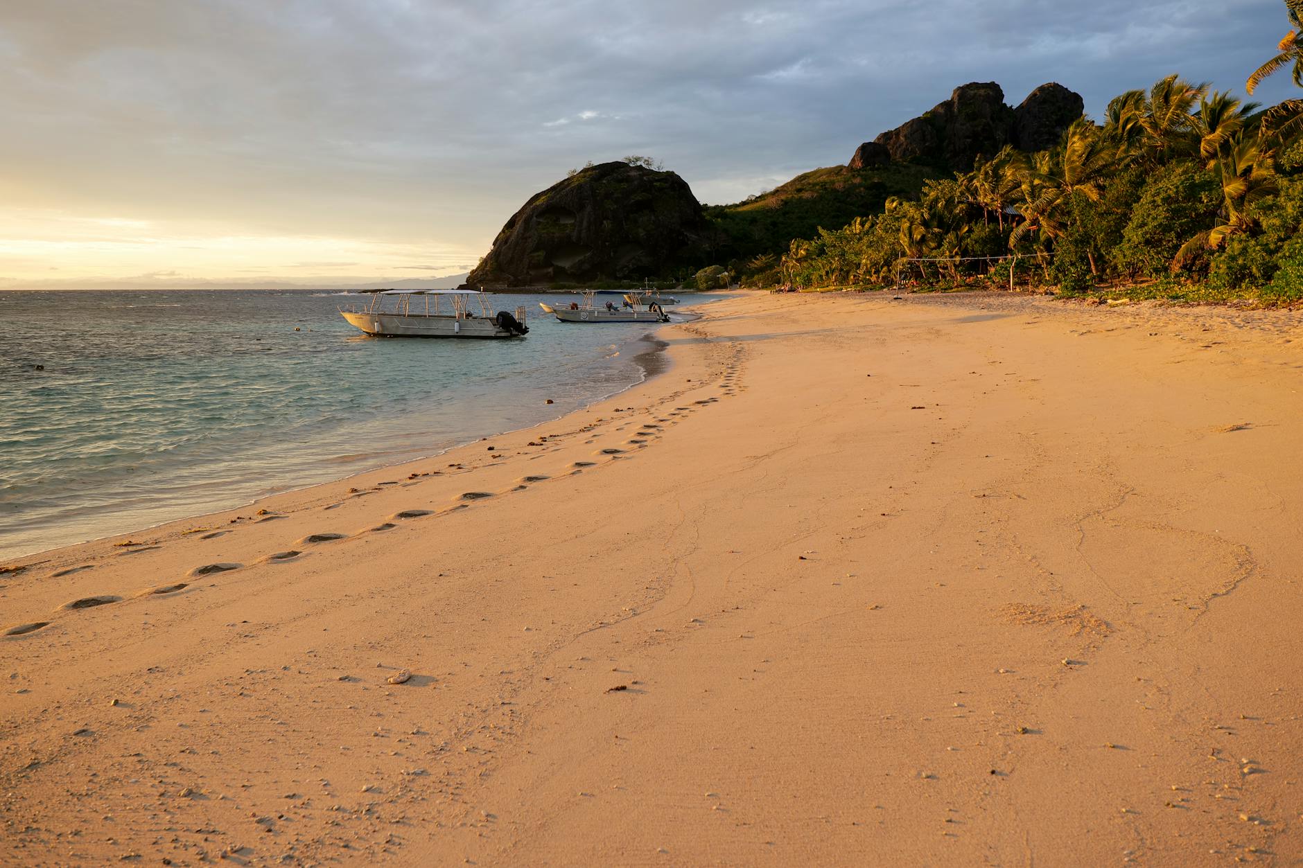 Yasawa Islands Fiji golden sand beach sunset boats anchored volcanic headland palm trees