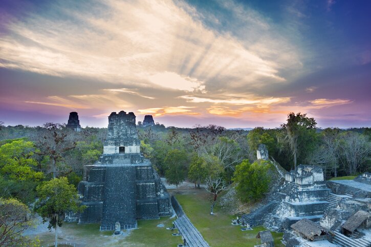 Tikal Guatemala Mayan pyramids rising above jungle canopy at sunset