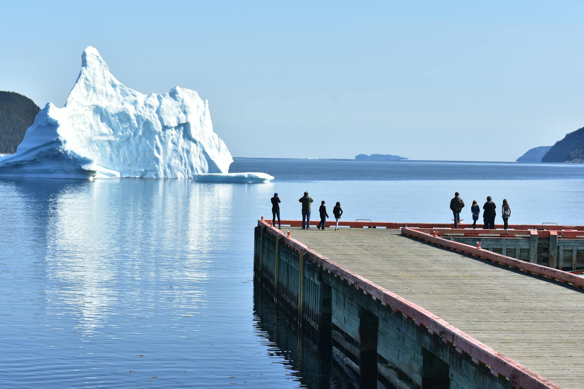 Iceberg Alley Newfoundland Canada visitors on dock watching massive iceberg float past