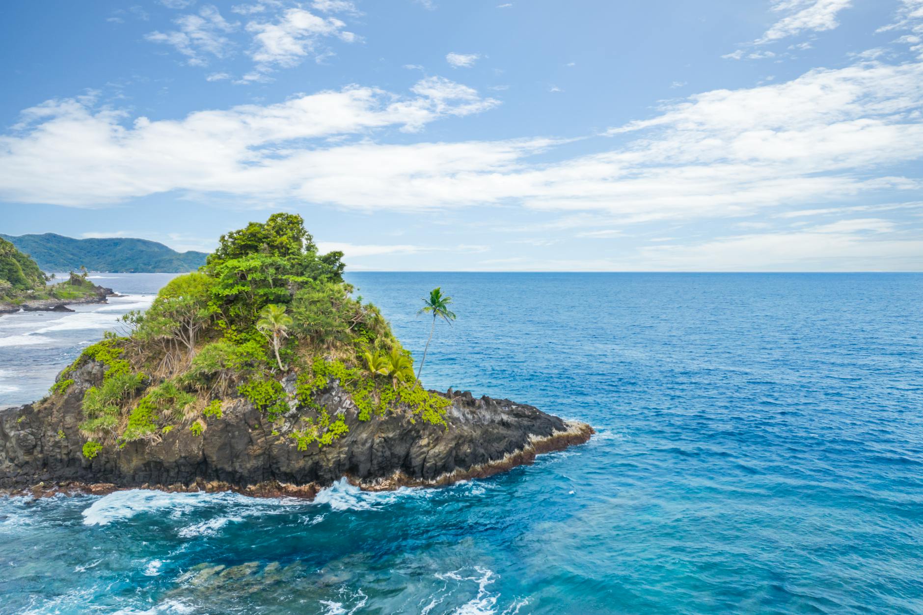 Samoa rocky islet lush tropical vegetation palm tree Pacific Ocean