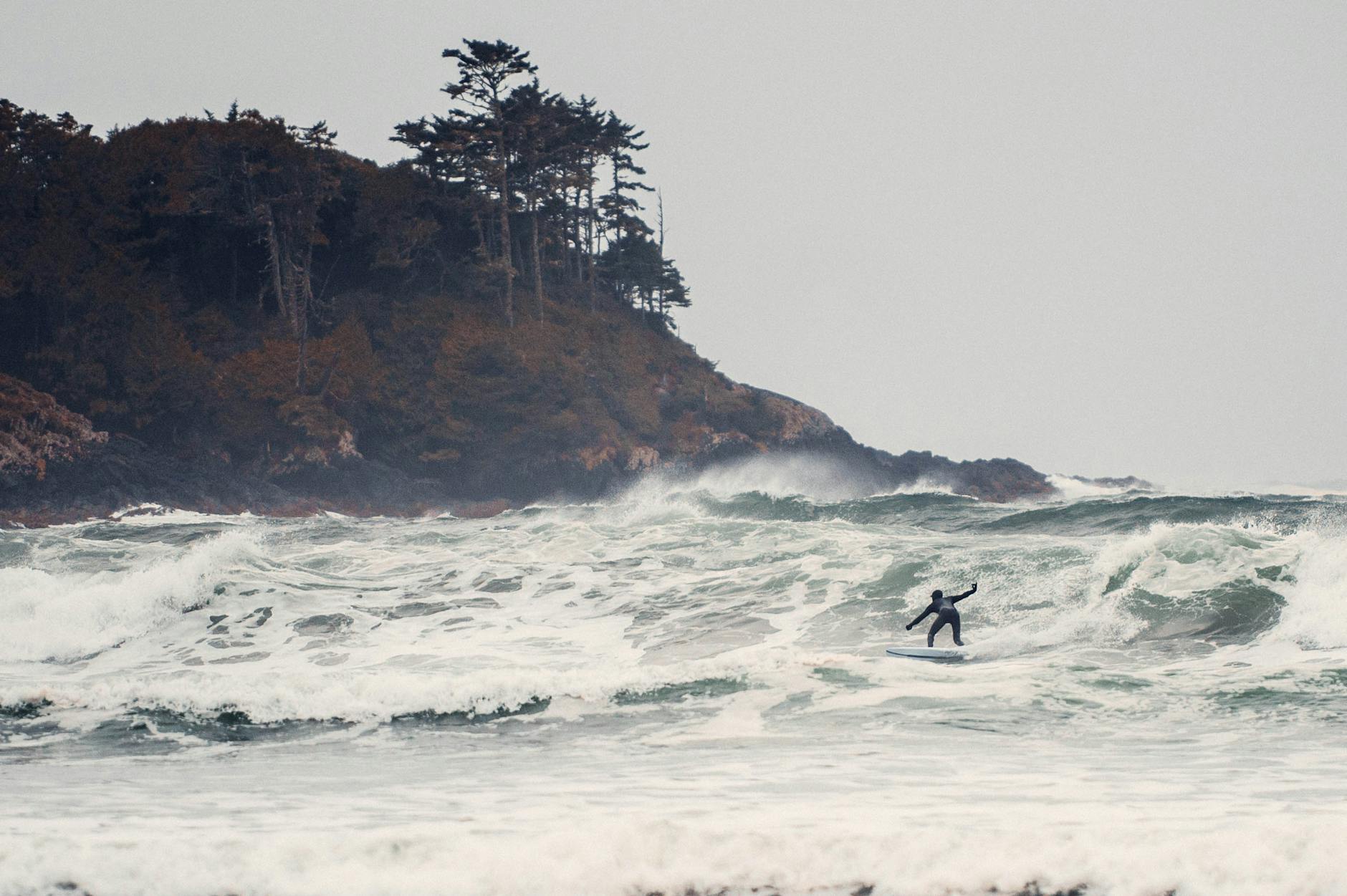 Experience the thrill of surfing against dramatic waves near Tofino, BC, Canada.