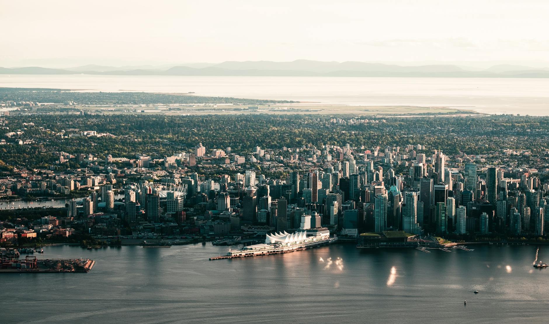 Scenic aerial shot of Vancouver's skyline with waterfront and mountains in the background.