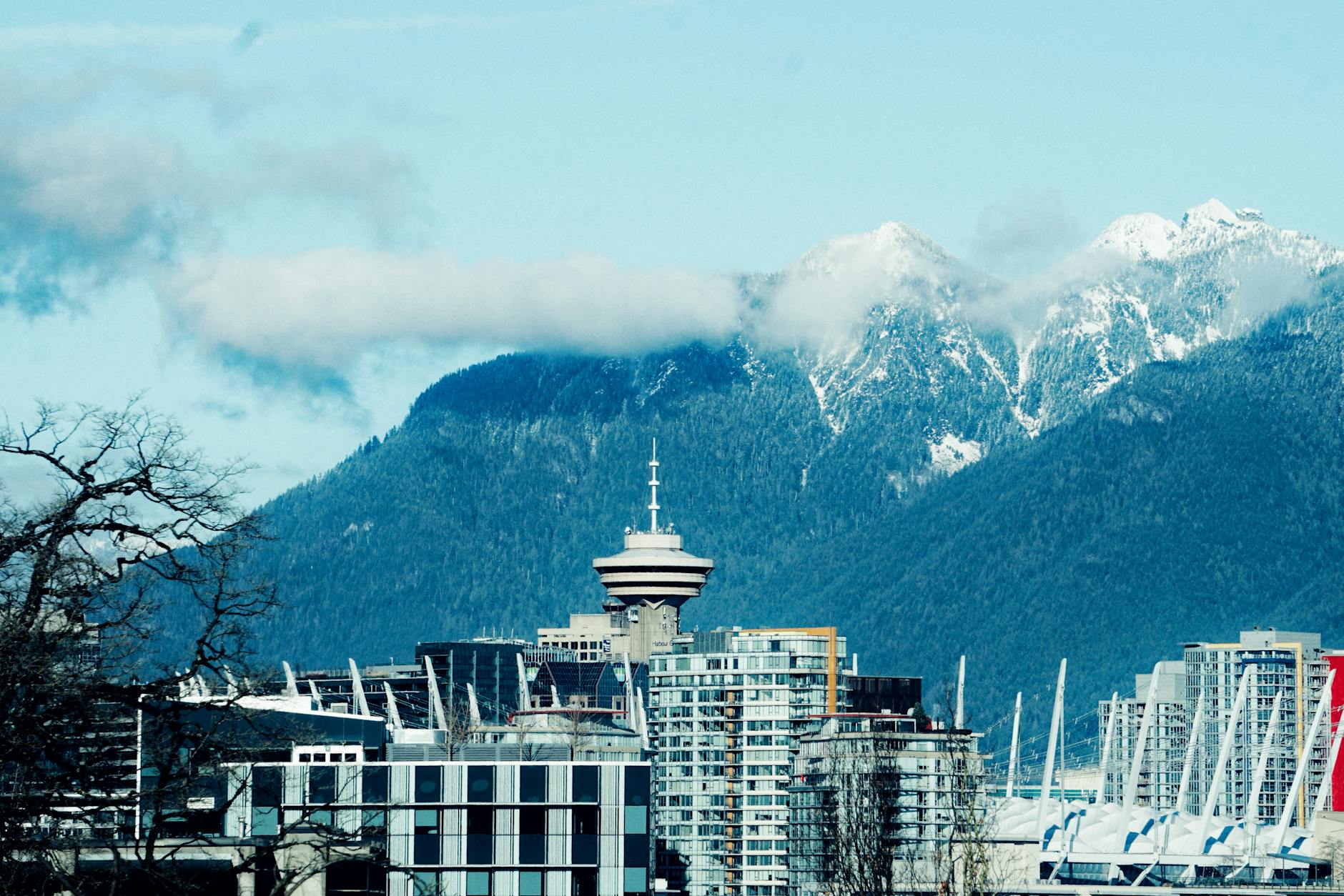 Vancouver's iconic Harbour Centre against majestic mountains on a clear day.